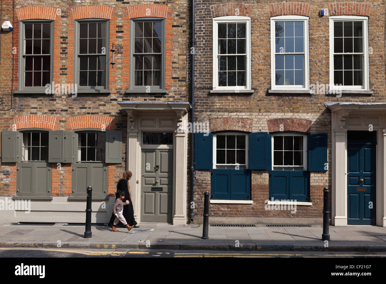 Una madre e figlia a piedi passato XVIII secolo case cittadine Georgiane su Fournier Street nell'East End di Londra. Foto Stock