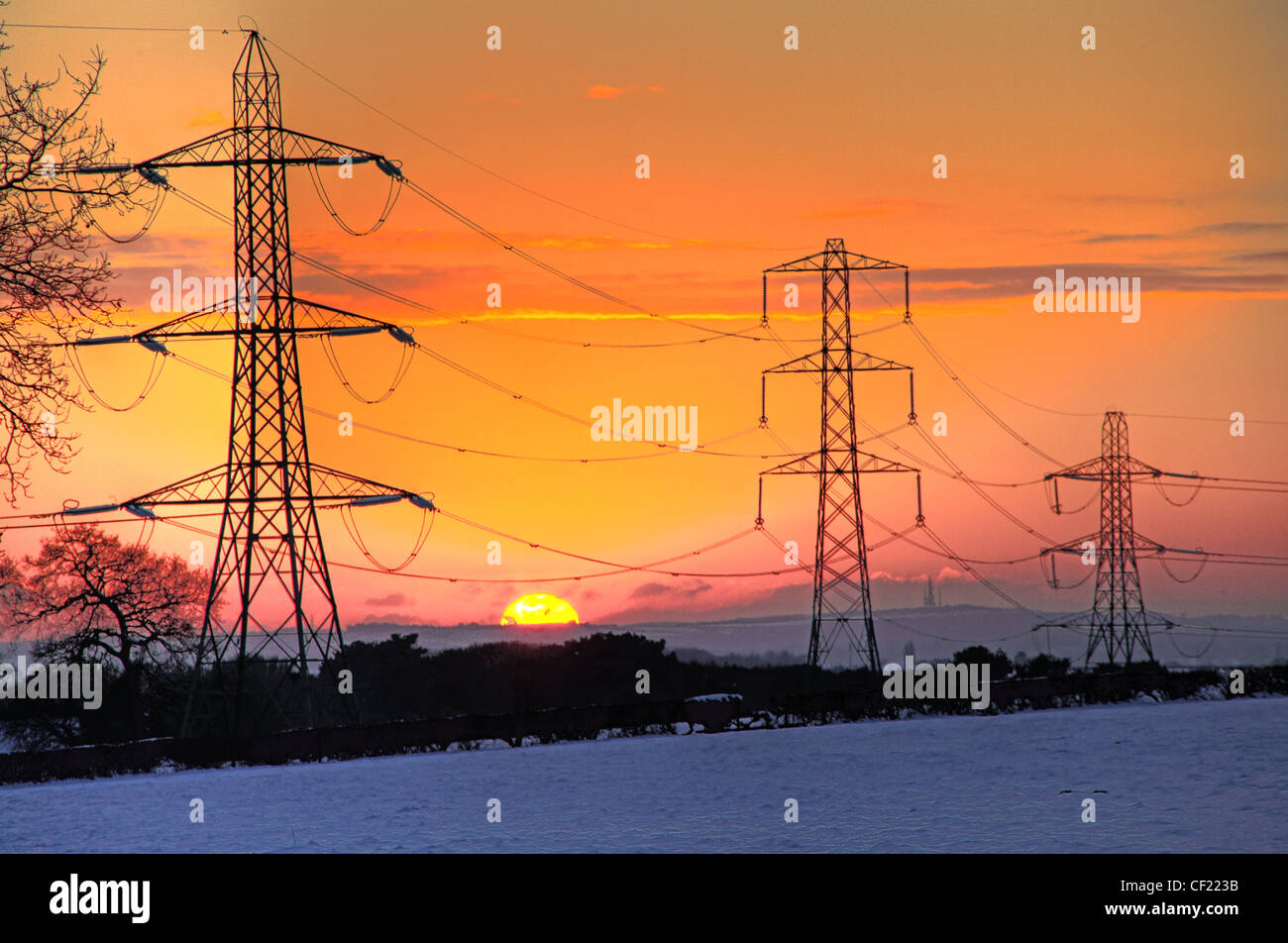 Nevoso inverno Cheshire linee elettriche al tramonto Foto Stock