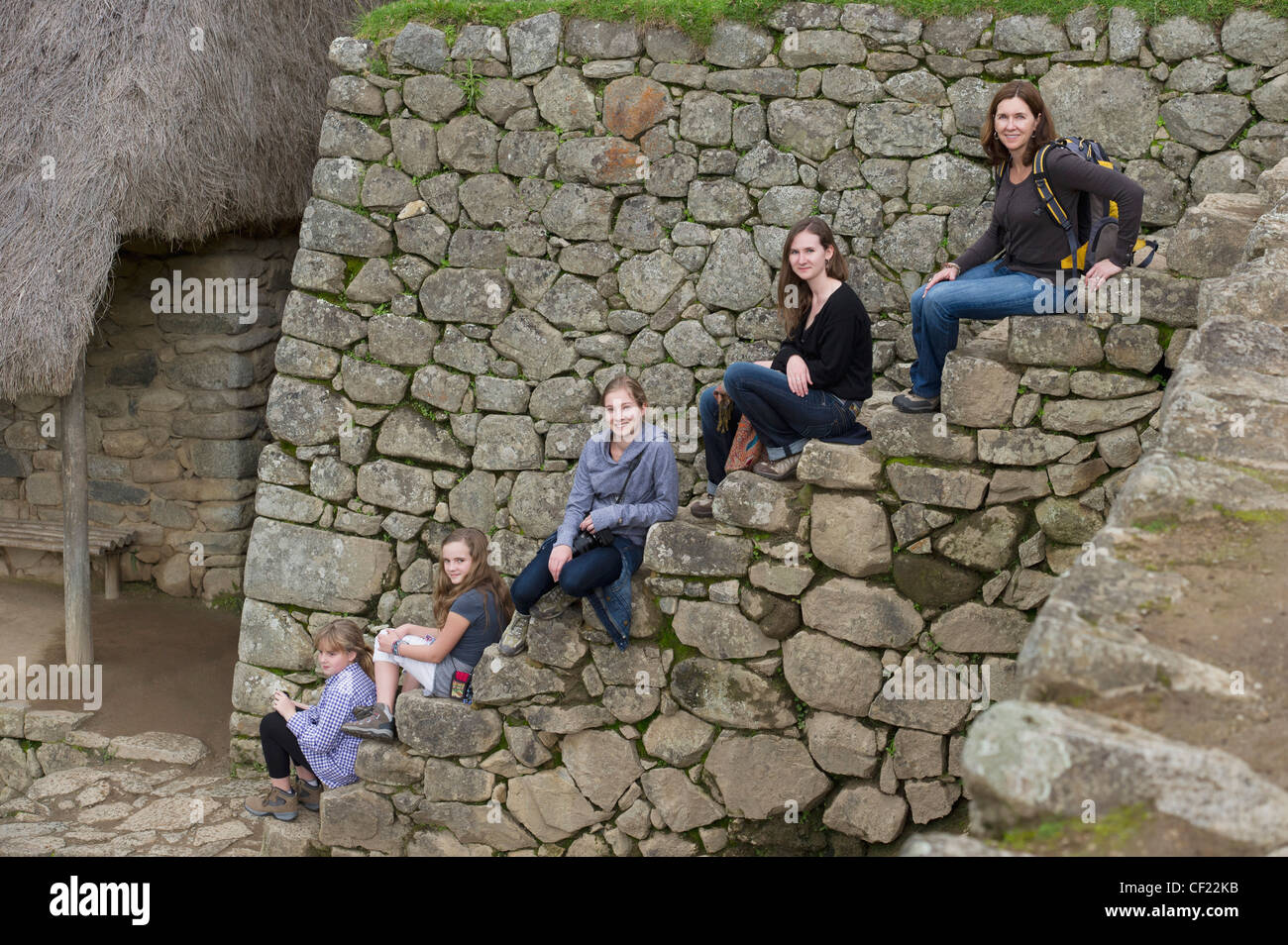 Cinque ragazze posti seduti sui gradini di Machu Picchu; Perù Foto Stock