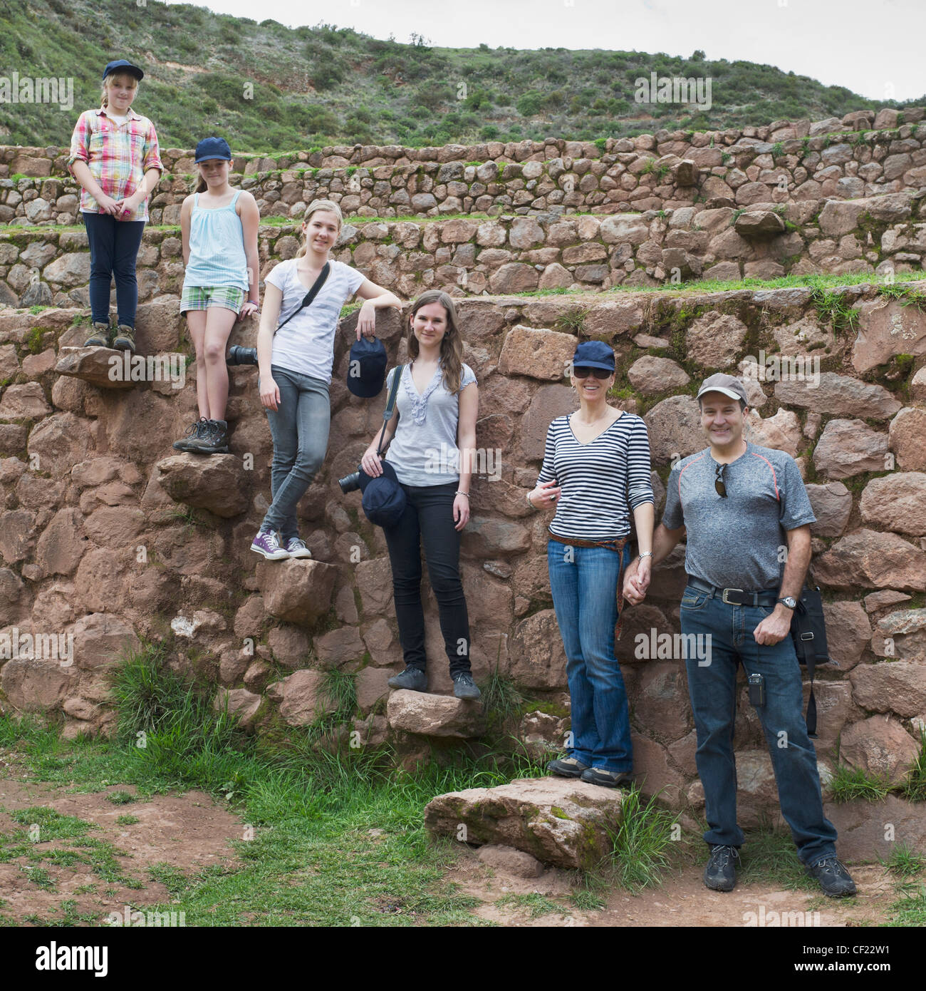 Una famiglia sta ponendo su rocce alle rovine Inca; Moray Perù Foto Stock