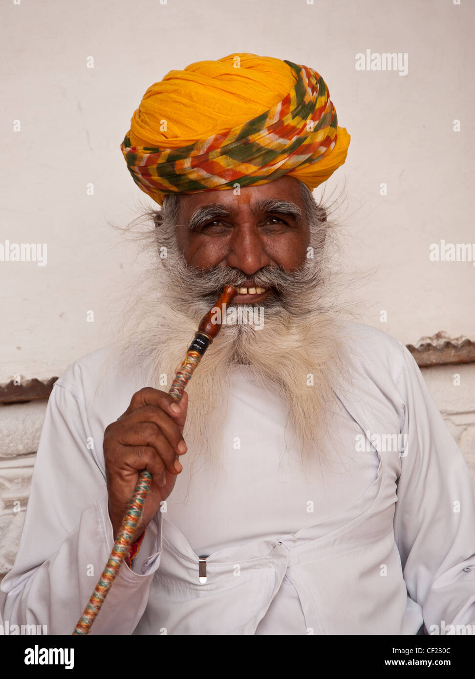 Uomo indù indossando turbante giallo di fumare in Rajasthan, India Foto Stock