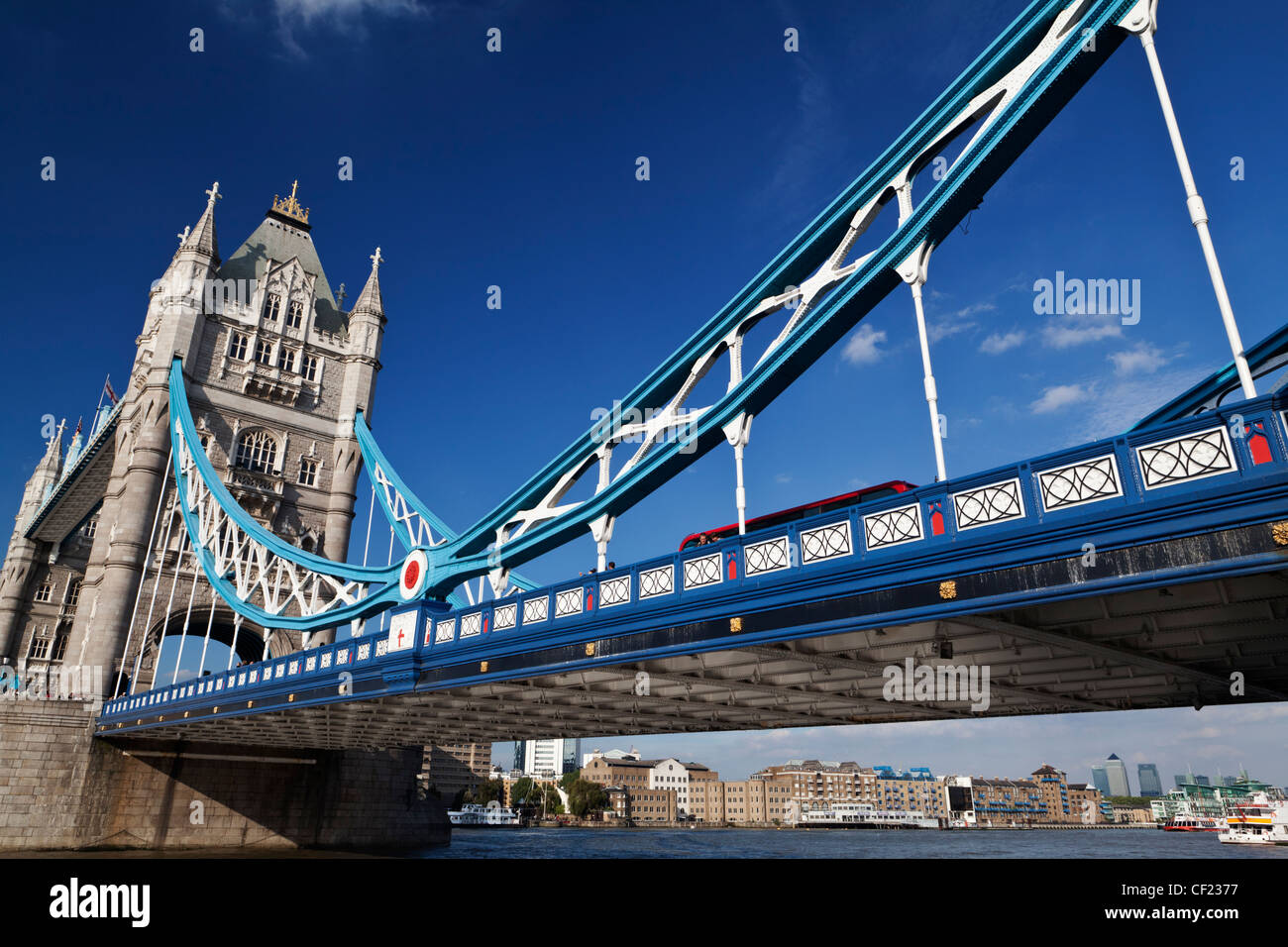 Un rosso London bus attraversando il fiume Tamigi oltre il Tower Bridge, uno di Londra più famosi e iconici punti di riferimento. Foto Stock