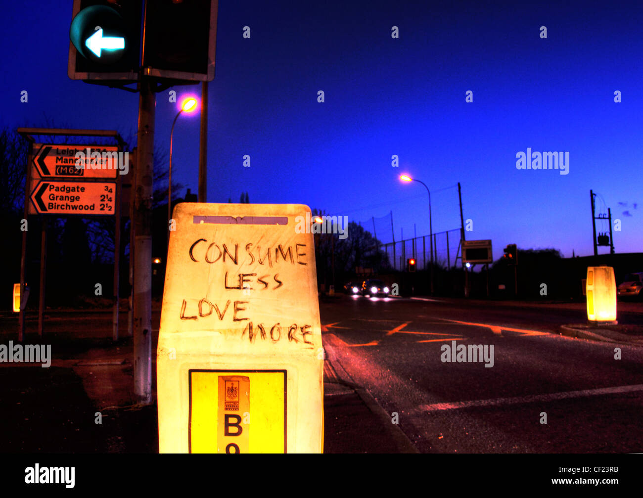 Comsume meno amore più scrawled su una strada beacon, Padgate / legno di betulla A57 Warrington al crepuscolo. Foto Stock