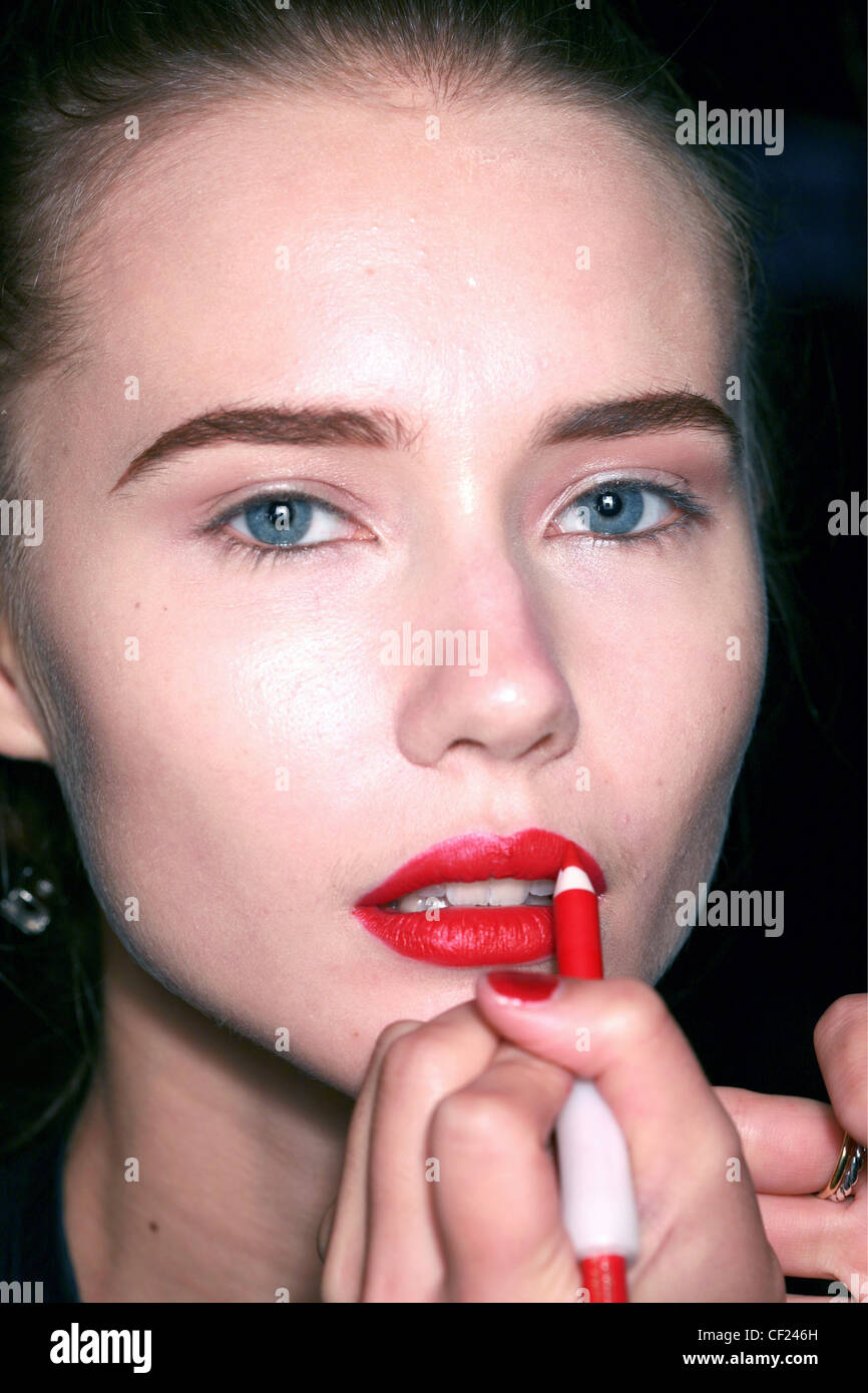 Il backstage di PPQ Londra pronto a indossare Primavera Estate Red labbro matita essendo applicato su bruna indossa femmina rosso profondo rossetto, Foto Stock