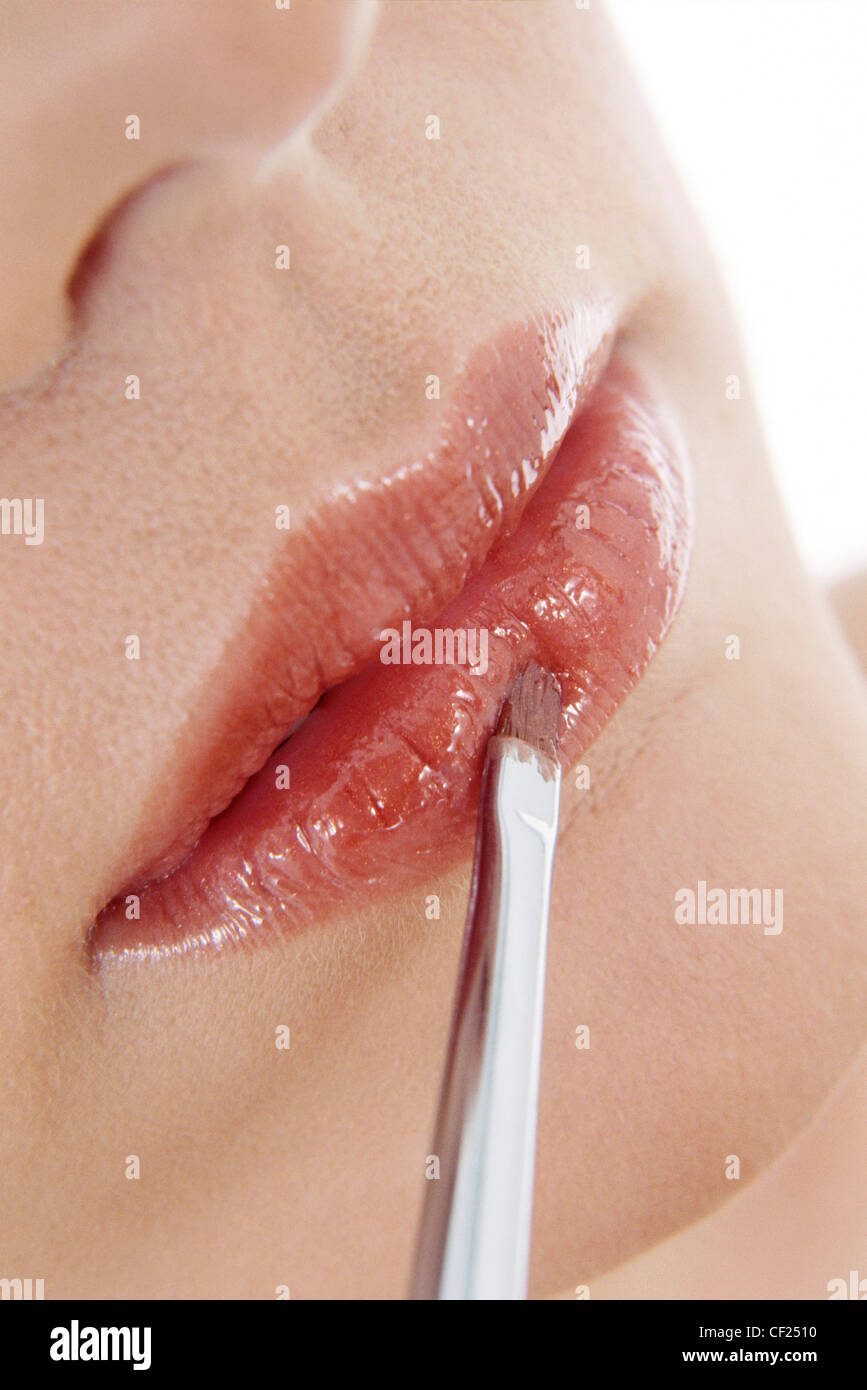 Close up femmina rosso applicazione lip gloss con labbro pennello Foto Stock