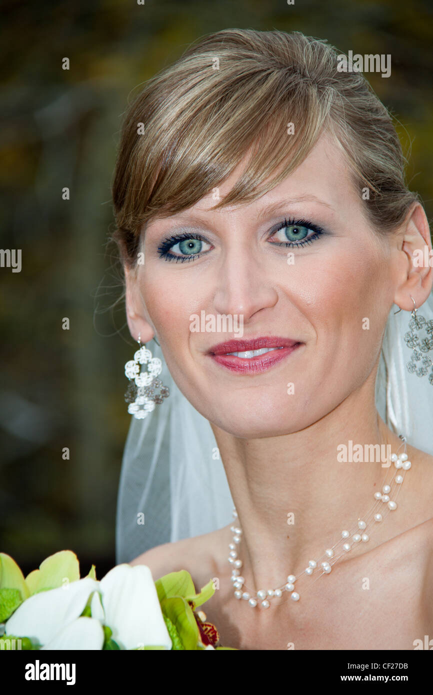 Sorridente sposa indossa gioielli nuziale guardando la fotocamera Foto Stock