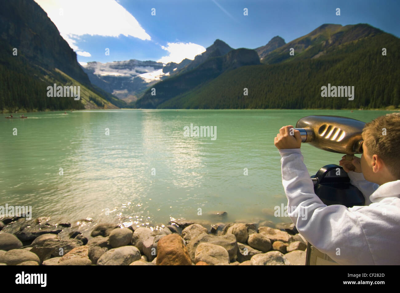 Un ragazzo alla ricerca attraverso il binocolo in una vista delle montagne sopra il Lago Louise; Alberta Canada Foto Stock