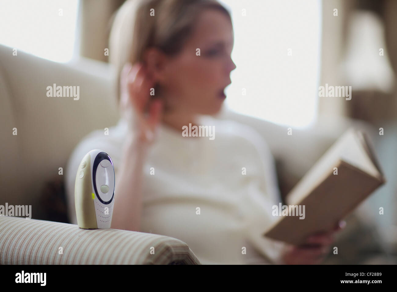 Una madre la lettura di un libro con un orecchio sul Baby Monitor; Giordania Ontario Canada Foto Stock