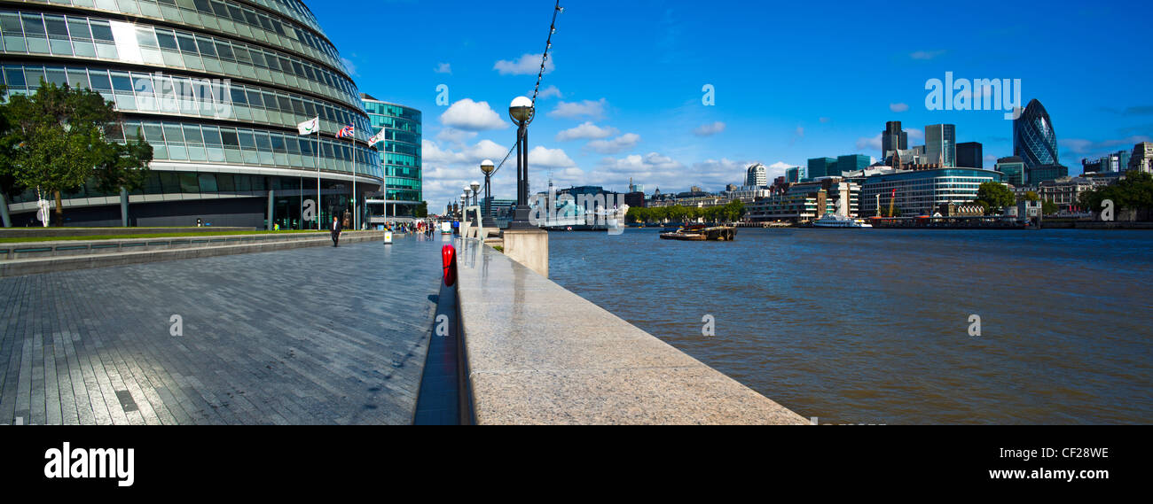 Vista lungo il Tamigi percorso verso la City Hall a south bank e la City di Londra sulla sponda nord del fiume Tamigi. Foto Stock