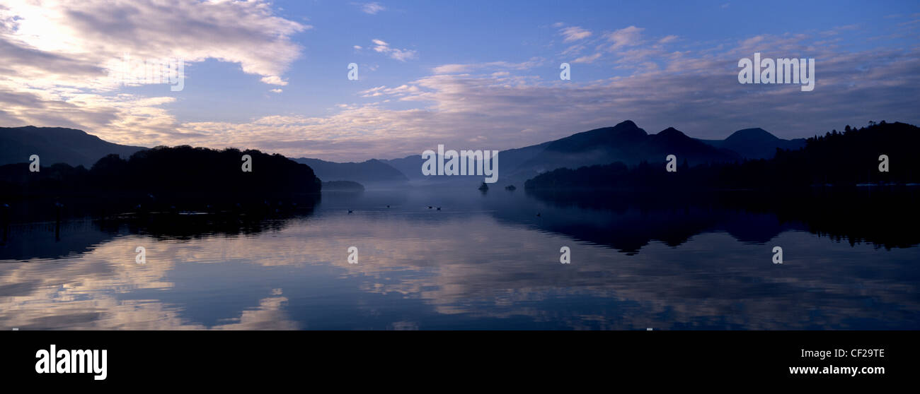 Parco Nazionale del Distretto dei Laghi. Sfondo di montagne riflessa nelle acque ancora di Derwentwater all'alba. Foto Stock