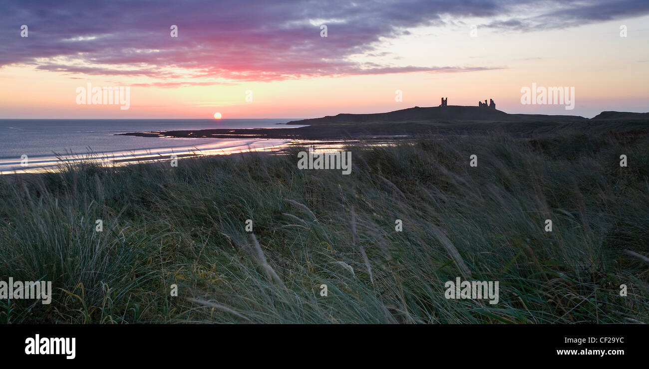 Sunrise sulle rovine del castello di Dunstanburgh sulla selvaggia costa di Northumberland. Foto Stock