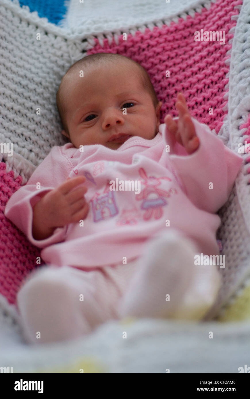 Un neonato baby femmina vestito in un babygrow rosa e rosa ponticello, in  un patchwork di maglia coperta Foto stock - Alamy