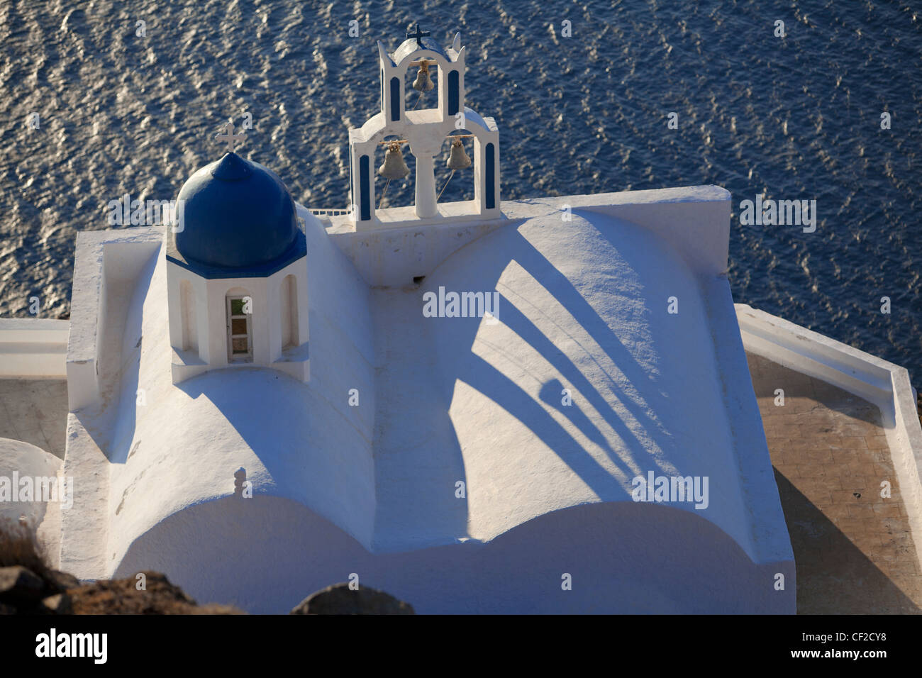 Una veduta aerea di un dipinto di bianco di chiesa con una cupola blu arroccato su di una scogliera sul mare a Santorini Foto Stock