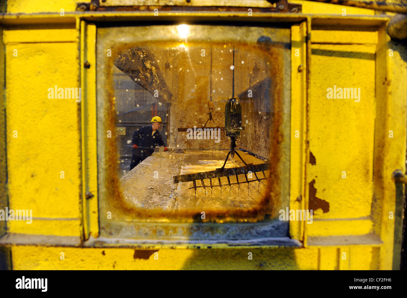 Un lavoratore si prepara in acciaio e sfiora in zinco fuso a un impianto di galvanizzazione. Foto Stock Un lavoratore si prepara in acciaio e sfiora in zinco fuso a un impianto di galvanizzazione. Foto Stock
