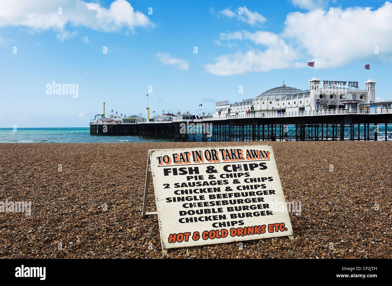Un segno pubblicità fast food sulla spiaggia di ciottoli vicino al molo di Brighton. Foto Stock