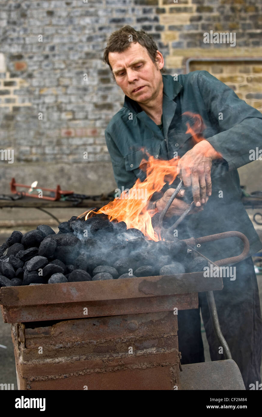 Un fabbro ferraio di mobili di metallo di riscaldamento in un forno aperto. Foto Stock