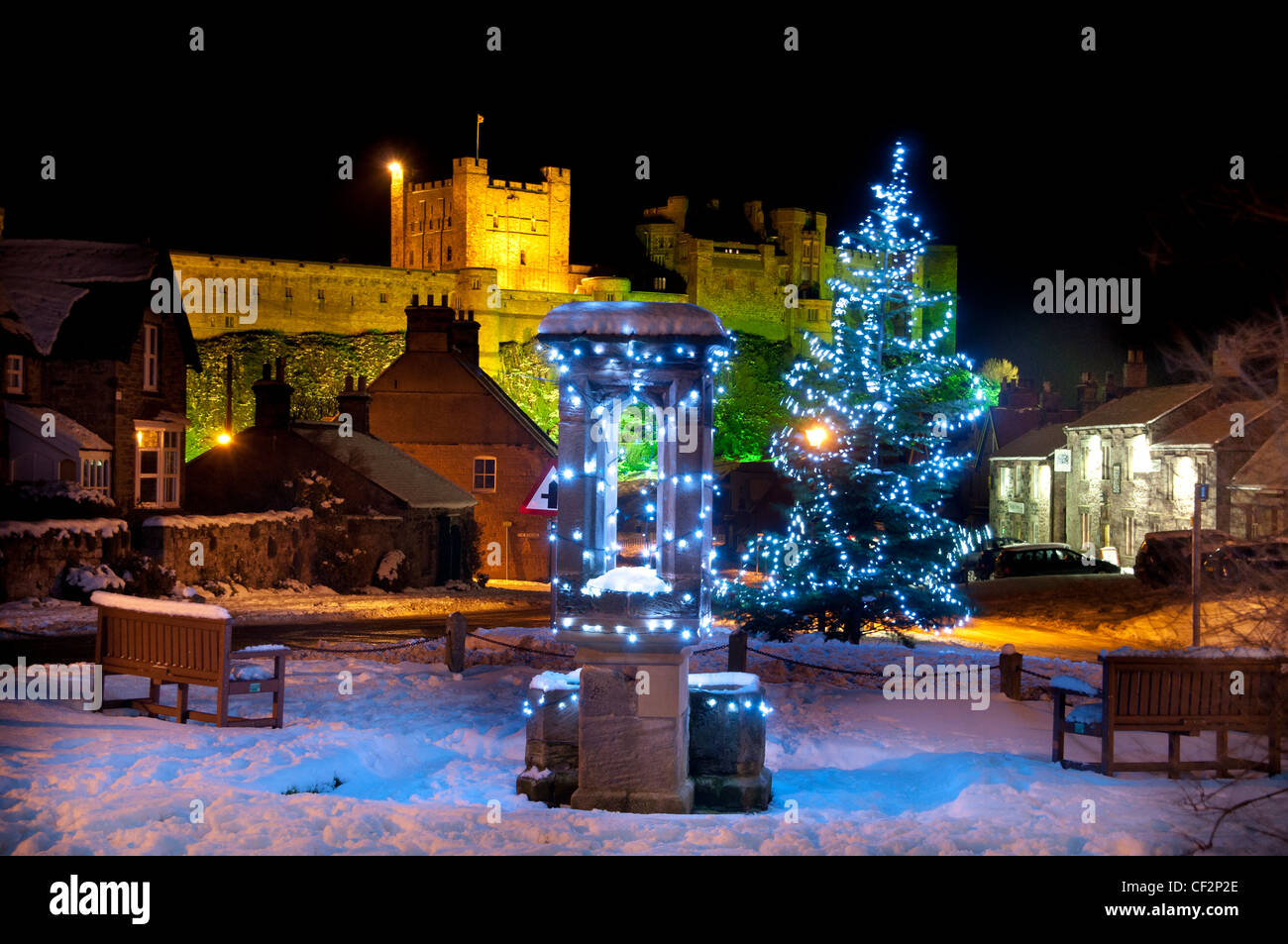 Le decorazioni di Natale nel villaggio di Bamburgh con il castello di Bamburgh, una volta residenza dei re di Northumbria, in ba Foto Stock