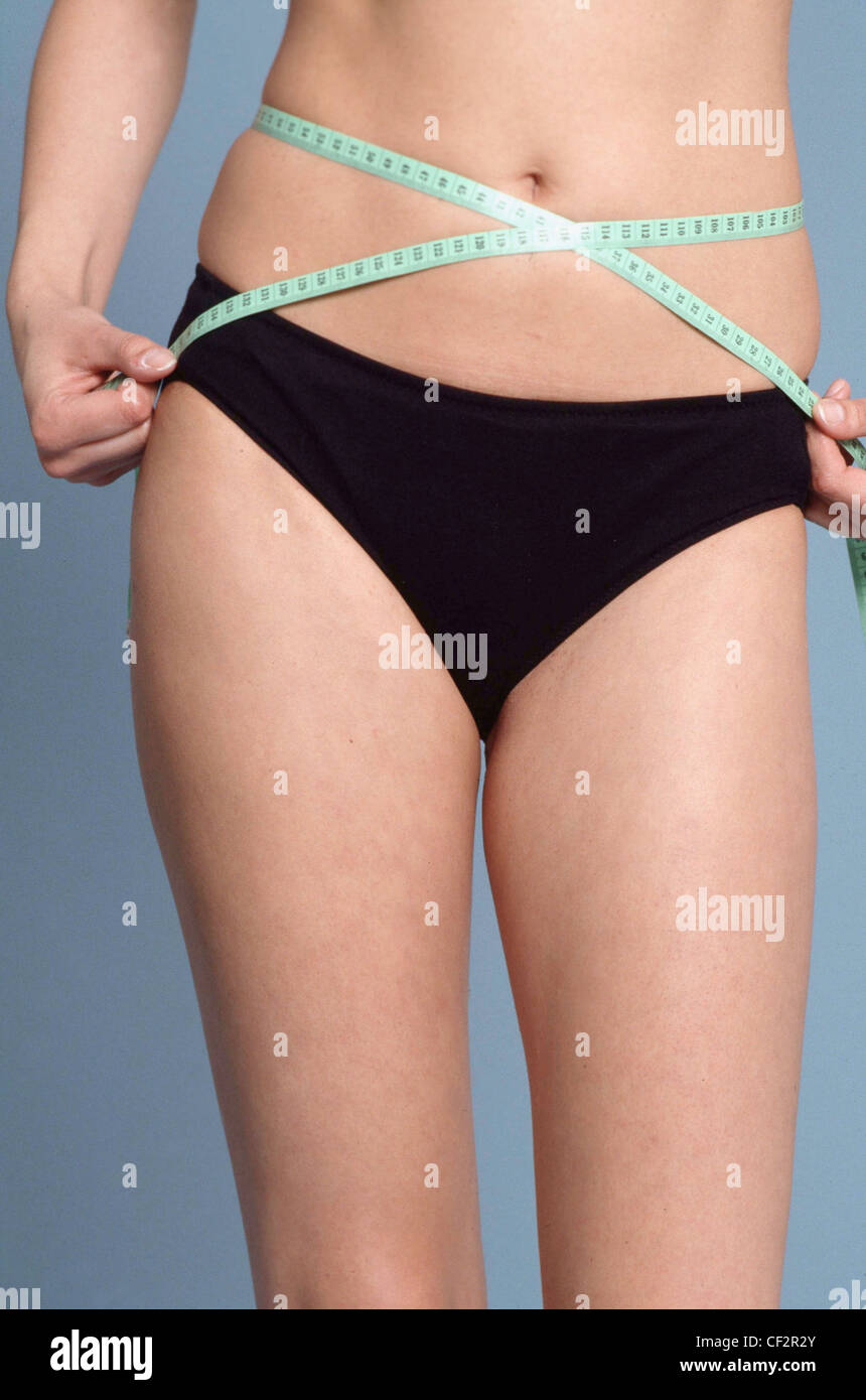 Femmina ritagliata vestita di nero mutande misurando la cintura verde con  nastro di misurazione Foto stock - Alamy