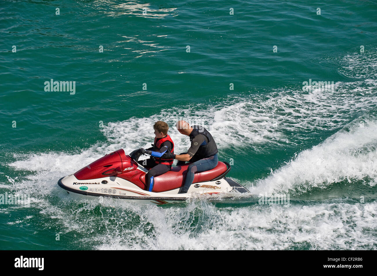 Un padre e figlio su un jet ski in mare al largo di Brighton. Foto Stock