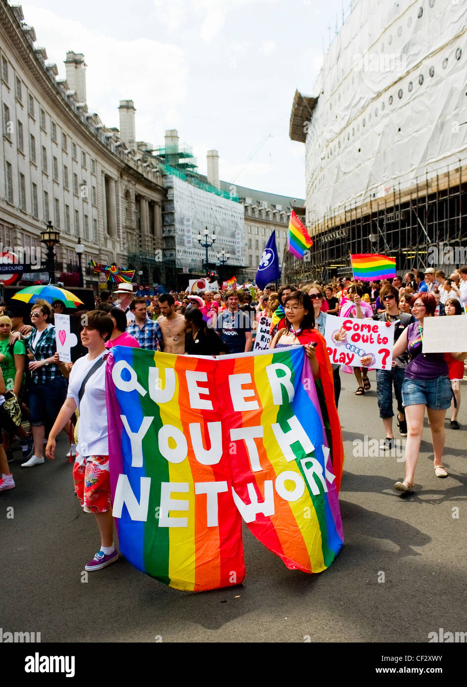 I membri del movimento queer Rete Giovanile sfilando con un coloratissimo banner arcobaleno al Pride London celebrazioni. Foto Stock
