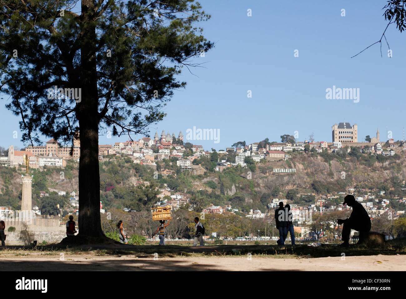 Sagome di persone e pane venditore a piedi vicino al lago Anosy nel centro di Antananarivo. Madagascar. Foto Stock