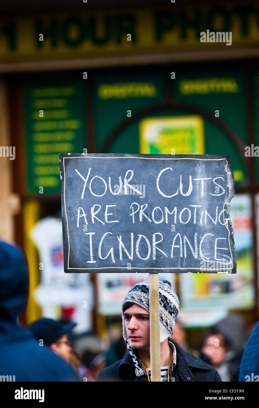Uno studente tenendo in mano un cartello a una manifestazione contro aumenti proposti in università tasse universitarie. Foto Stock