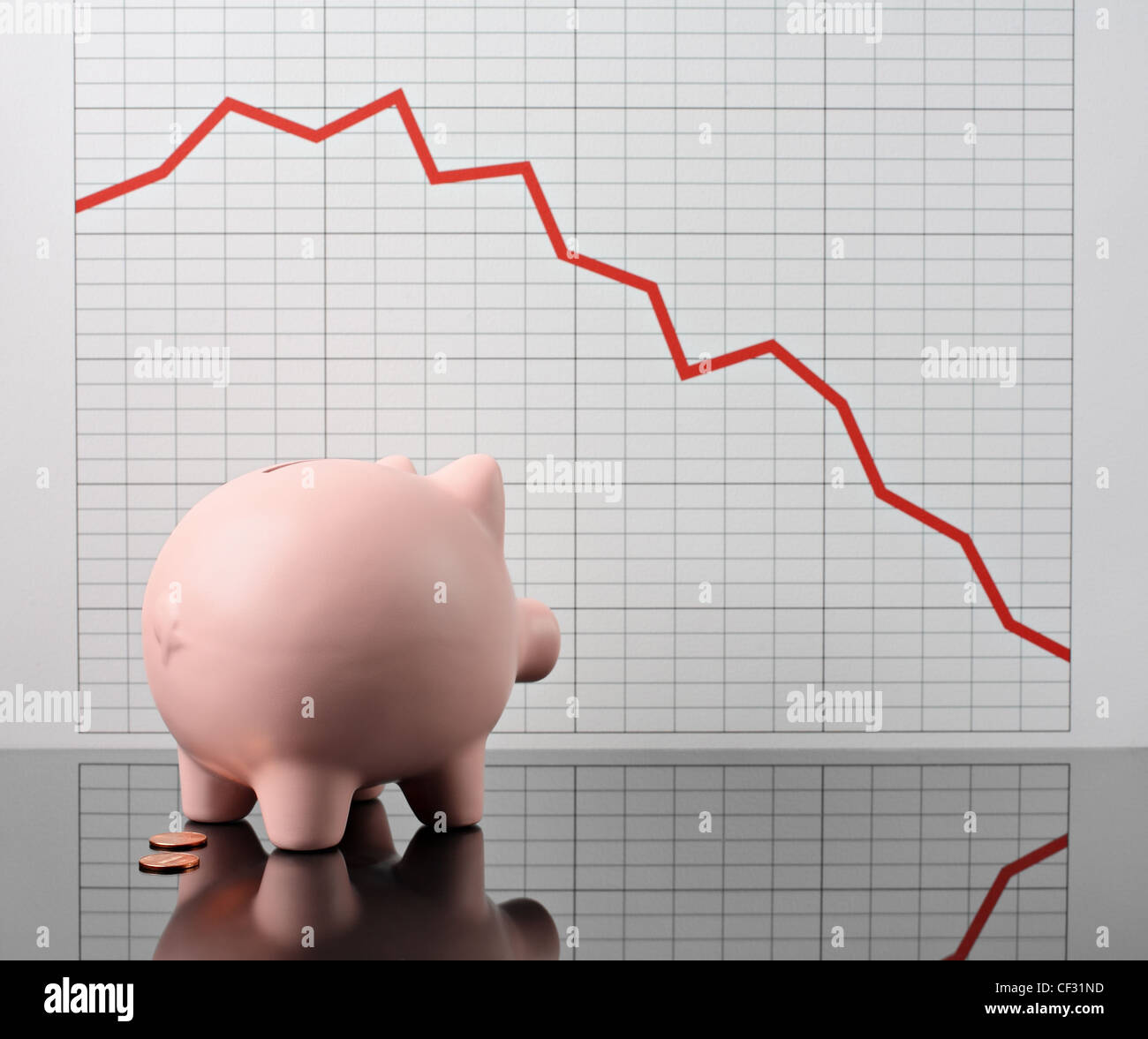 infelice piggy banca guardando grafico di declino economico Foto Stock
