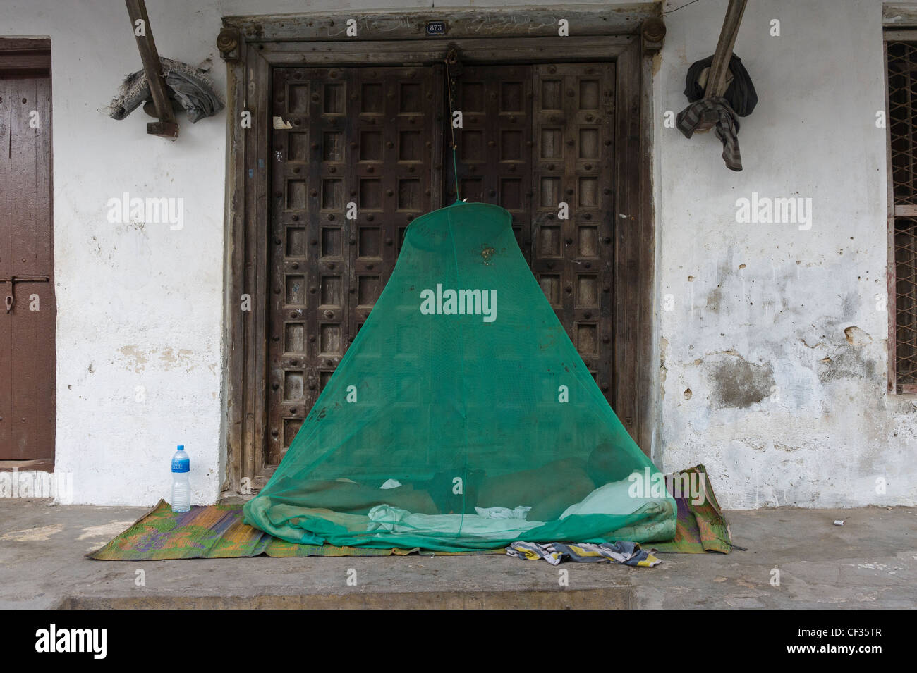 L'uomo dormire fuori sotto una zanzariera Stone Town Zanzibar Tanzania Foto Stock