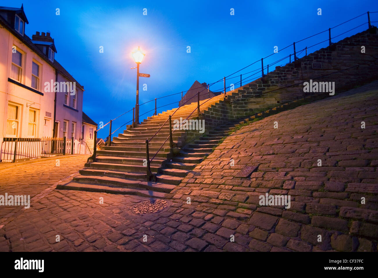 La base del famoso 199 gradini che portano nella città vecchia di Whitby illuminato da una tradizionale via la luce. Foto Stock