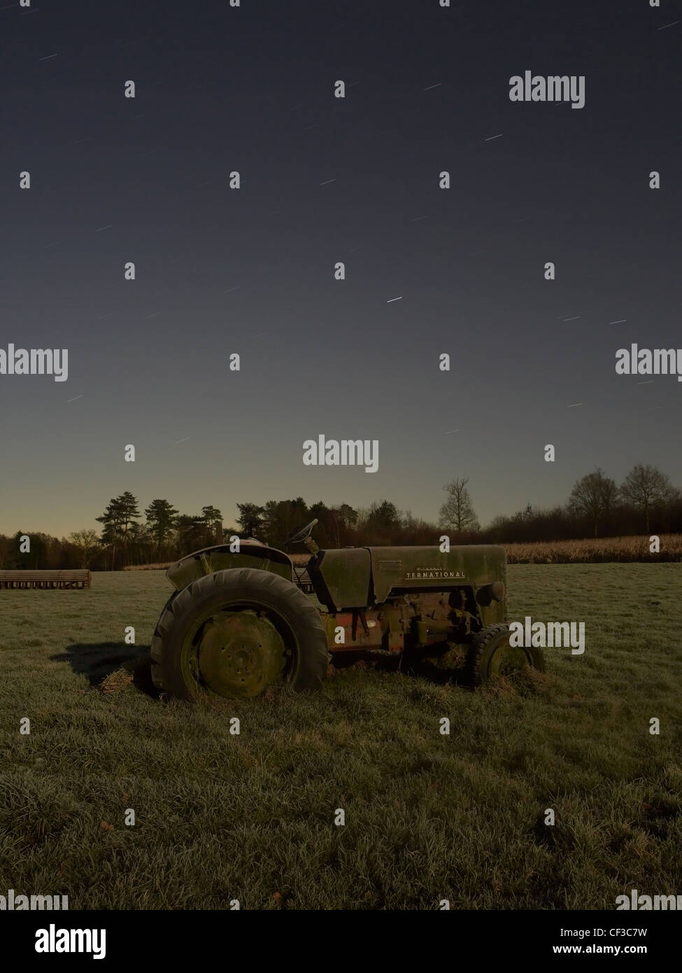 Un vecchio trattore si siede in un campo sotto un cielo notturno in Sussex. Foto Stock