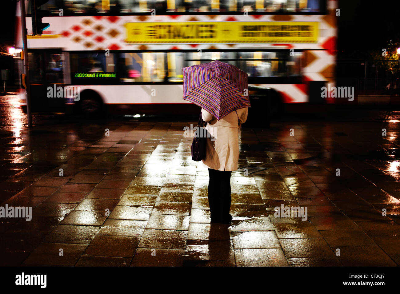 Una donna in piedi sotto un ombrello su Princes Street in attesa di qualcuno. Foto Stock