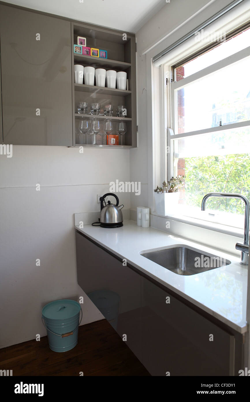Appartamento in Sydney piccola cucina galley con pietra bianca le superfici di lavoro e lucido grigio armadi Foto Stock