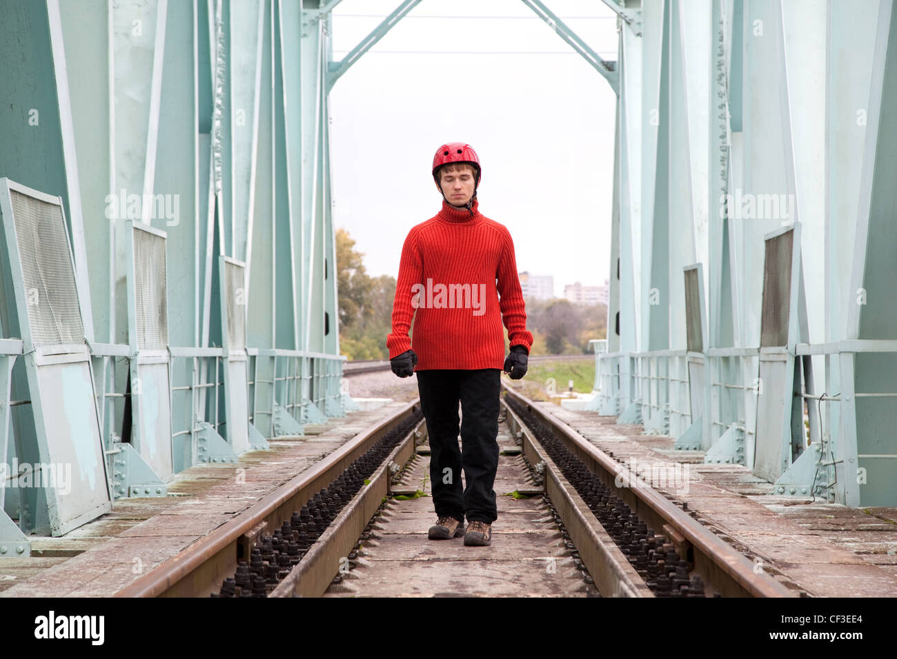 L'uomo lavoratore ciecamente in un casco si erge sulle rotaie bridge Foto Stock