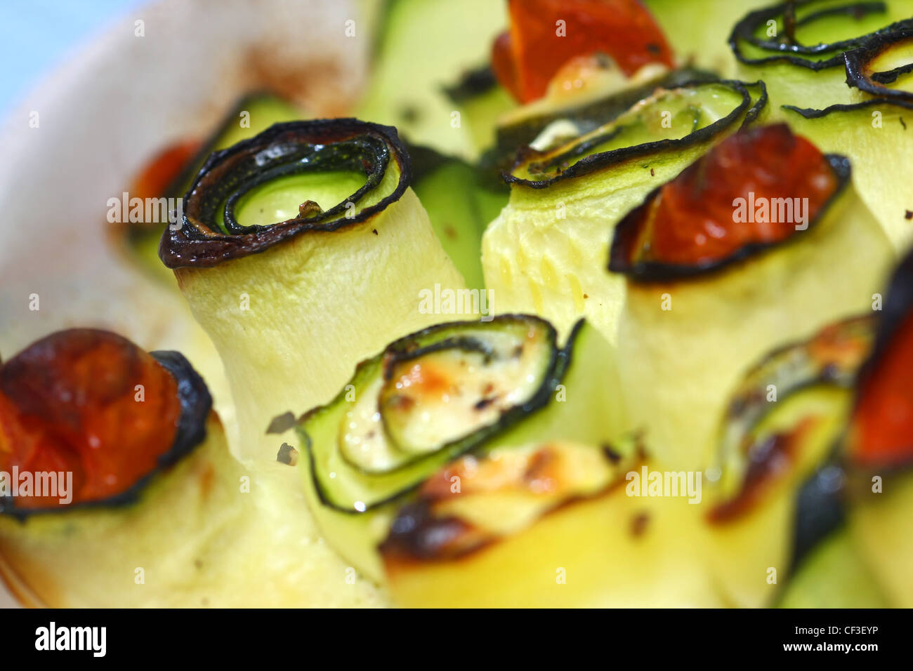 Rotoli di gette Ingredienti: medie zucchine, g formaggio feta, uovo, cucchiaino di origano, un paio di pomodori ciliegia, pepe e sale, cucchiai di olio Foto Stock