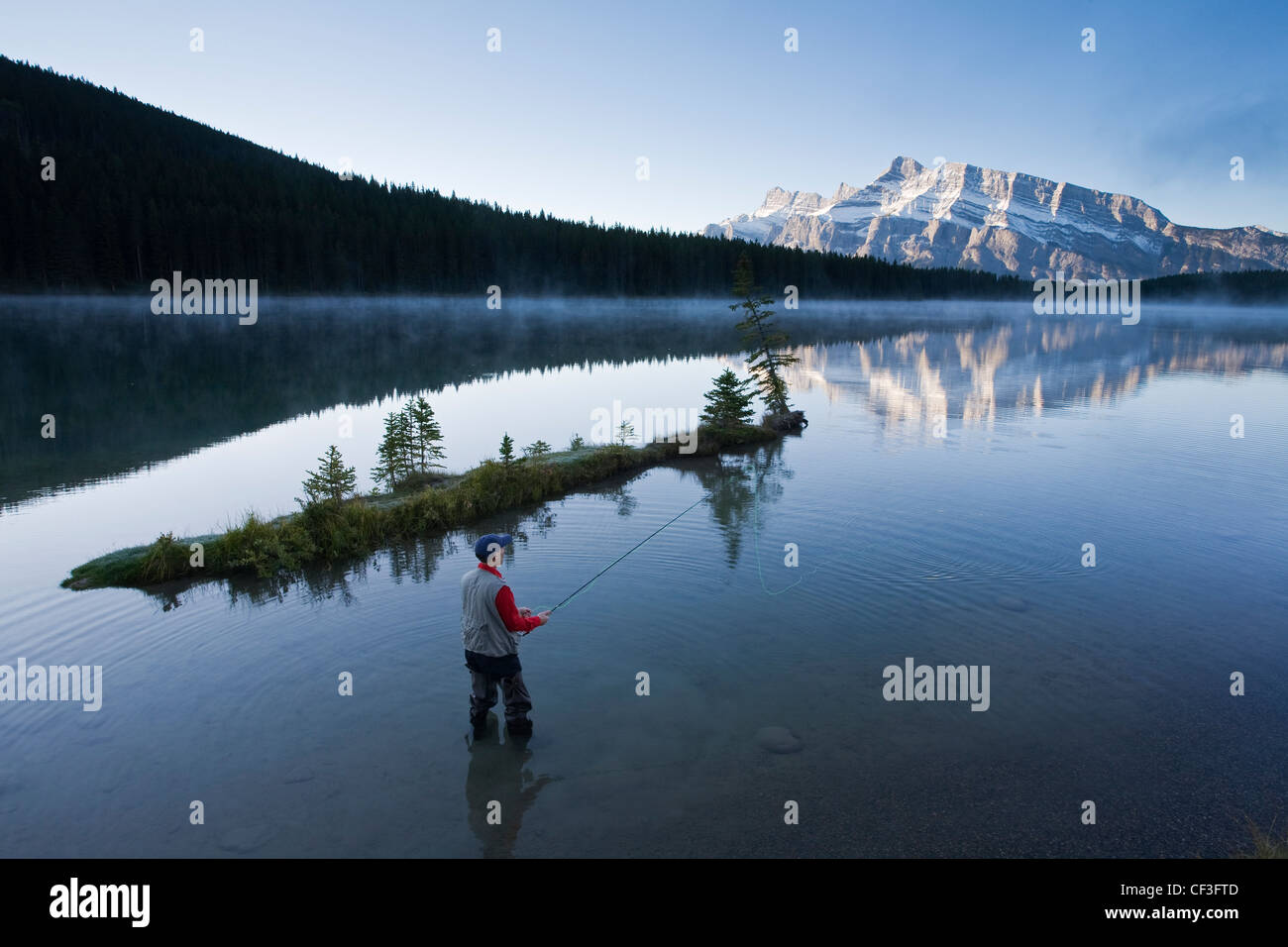 Medio di sesso maschile di età compresa la pesca con la mosca in due Jack Lake, il Parco Nazionale di Banff, Alberta, Canada. Foto Stock