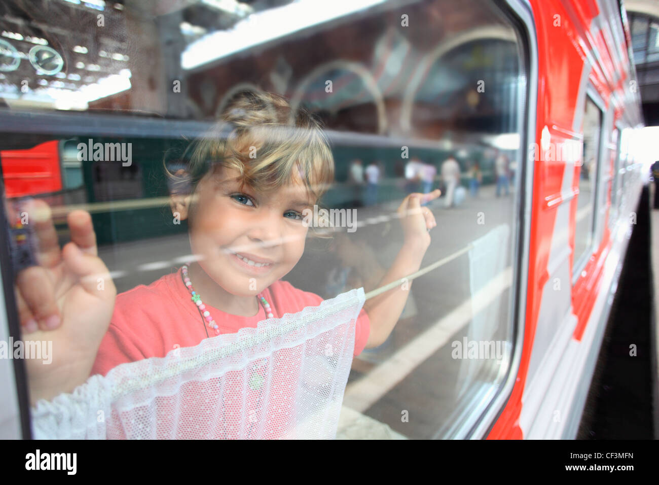 Sorridente bambina guardare dalla finestra del treno Foto Stock