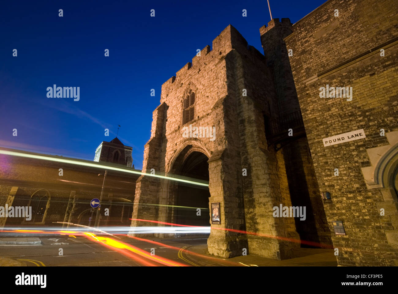 La Torre Westgate in Canterbury illuminata di notte con prove di luce dal traffico in transito. Foto Stock