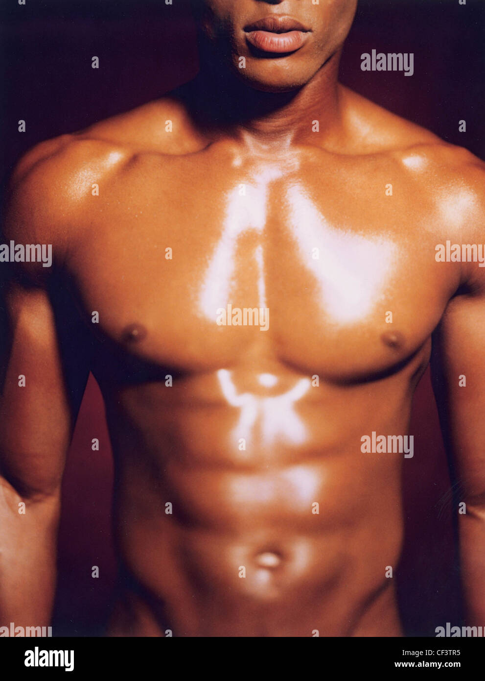 Tagliate il corpo superiore del maschio con ben definito di muscoli e olio sul petto Foto Stock