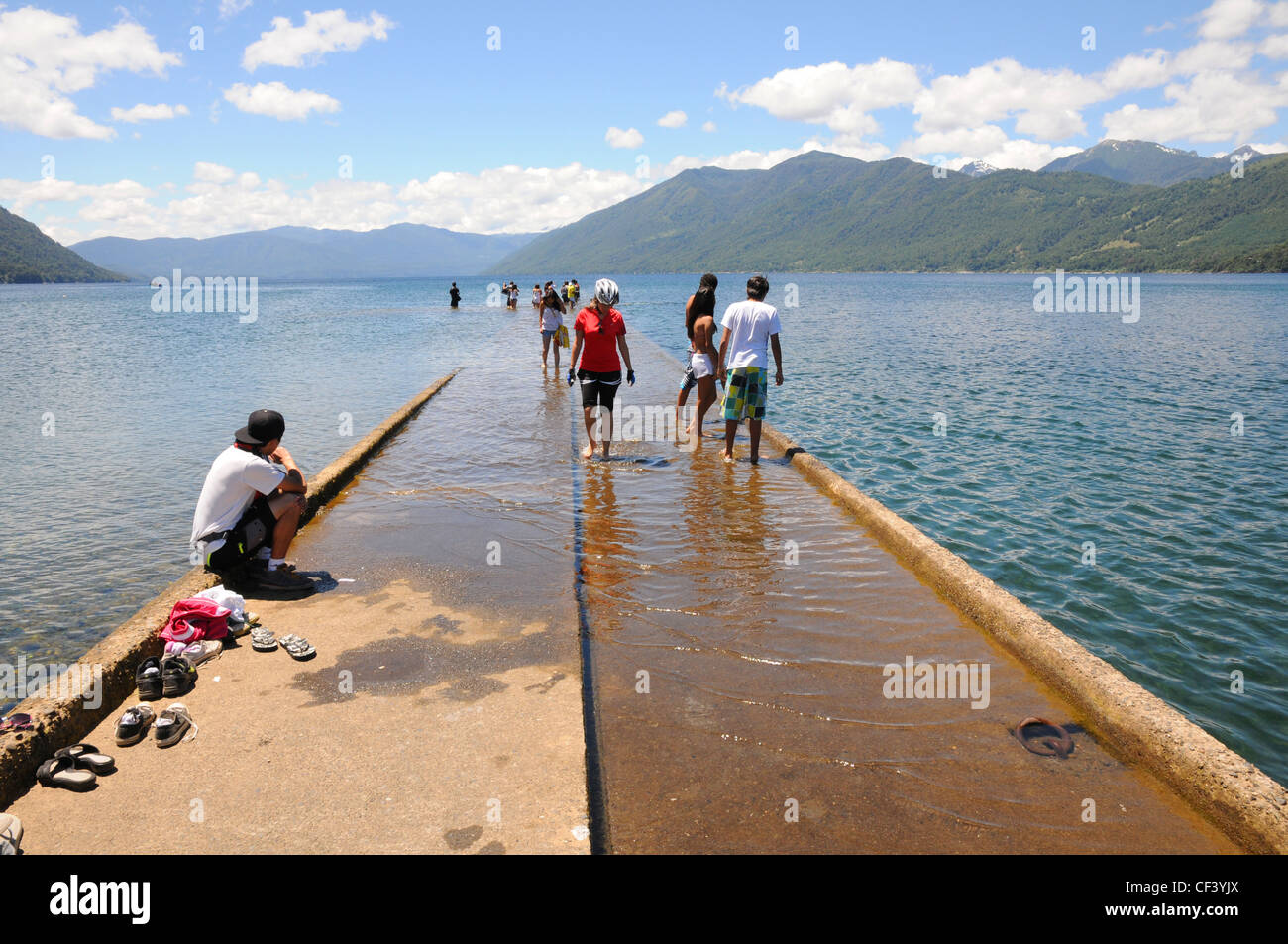 I turisti e i locali a piedi su semi-sommersa imbarcadero, Lago Villarrica, Araucania, Cile. Foto Stock