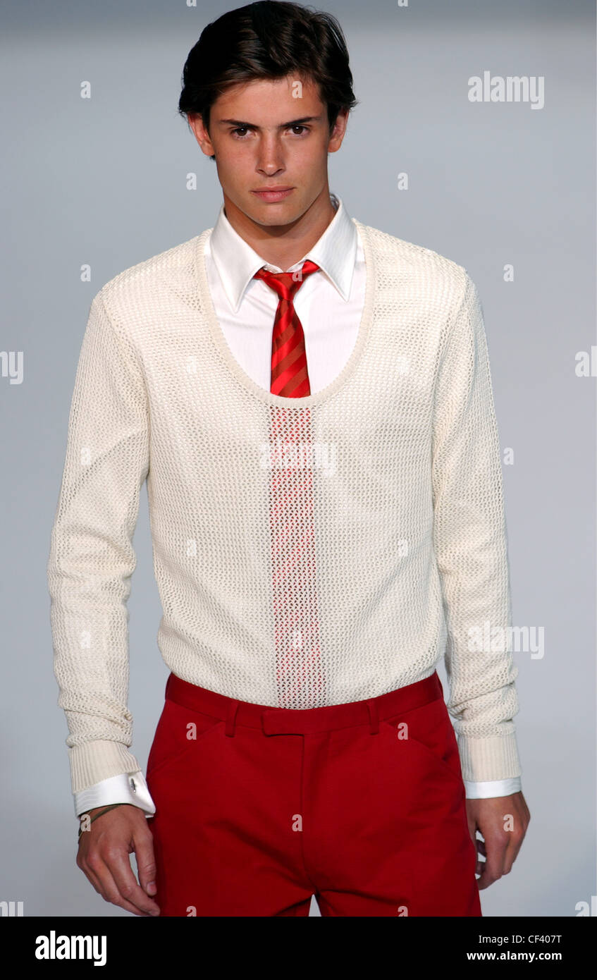 Givenchy Paris Menswear S S modello maschile che indossa la crema rivelando  un maglione sopra una camicia bianca e cravatta rossa con pantaloni rossi  Foto stock - Alamy