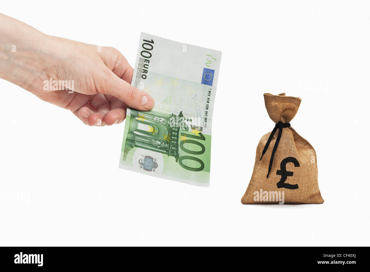 Un Euro 100 bill è tenuto in mano. Nelle vicinanze si trova un sacco di denaro con una libbra di cambio segno. Foto Stock