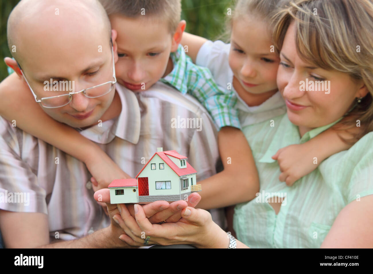 Famiglia con due bambini è mantenere wendy house nelle loro mani e lo sta guardando. focus su wendy house. facce in fuori fuoco. Foto Stock