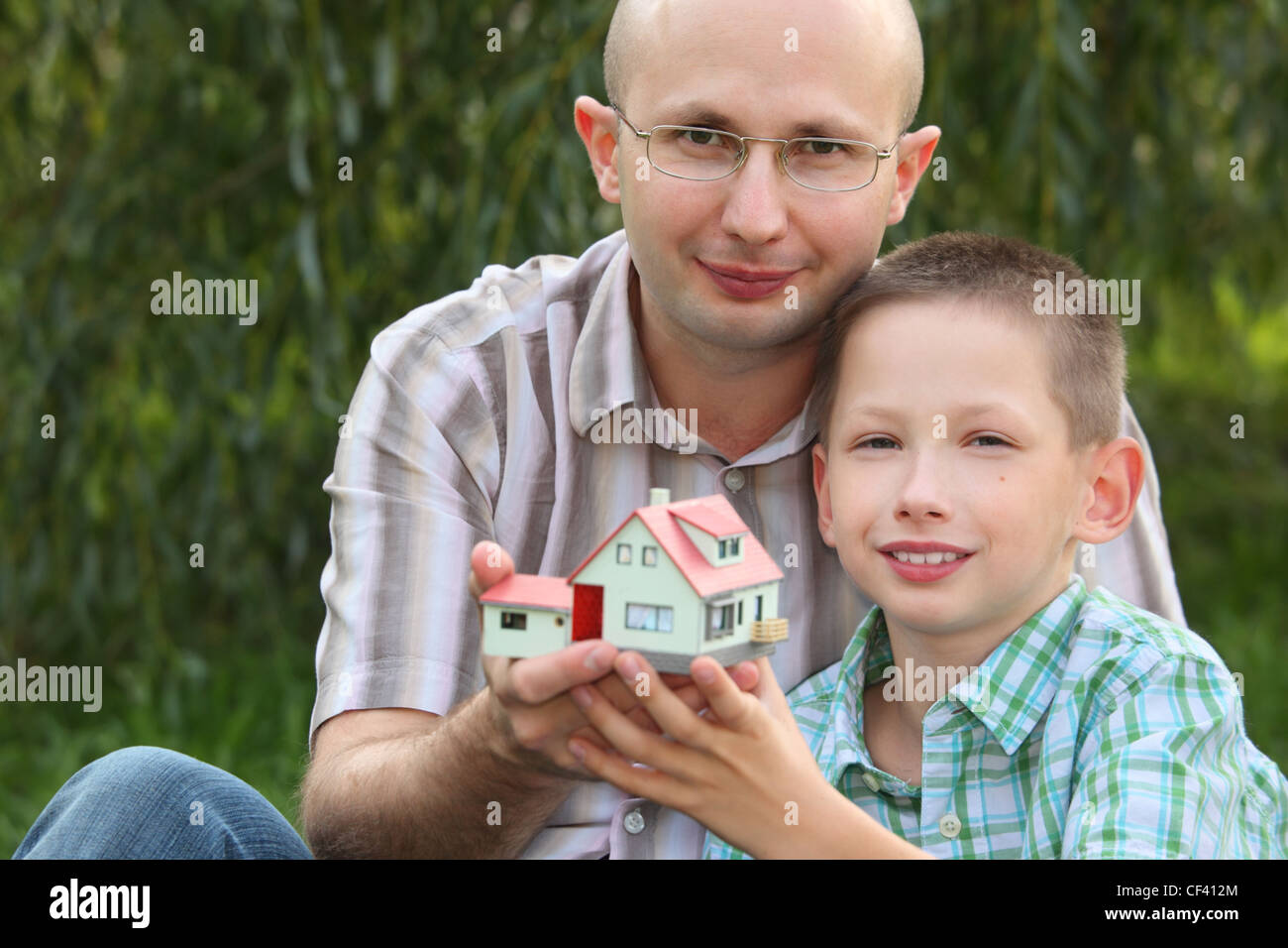 Padre e figlio mantenendo nelle loro mani wendy house e guardando la fotocamera. focus sul volto del padre. wendy house di fuori fuoco. Foto Stock