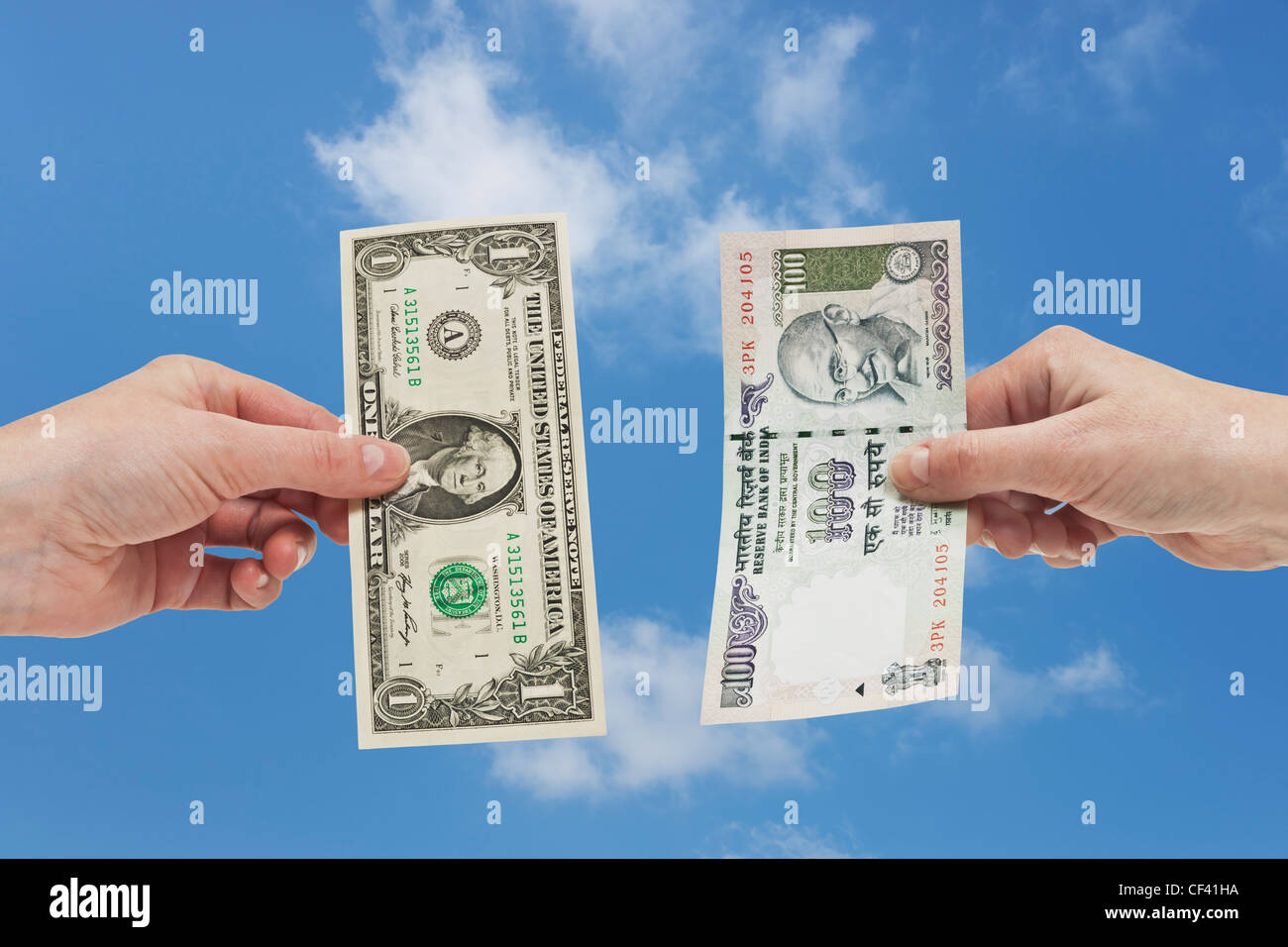 Uno 1 U.S. Dollaro è tenuto in mano. Dall'altro lato un Indian 100 rupie bill è tenuto in mano, lo sfondo del cielo. Foto Stock