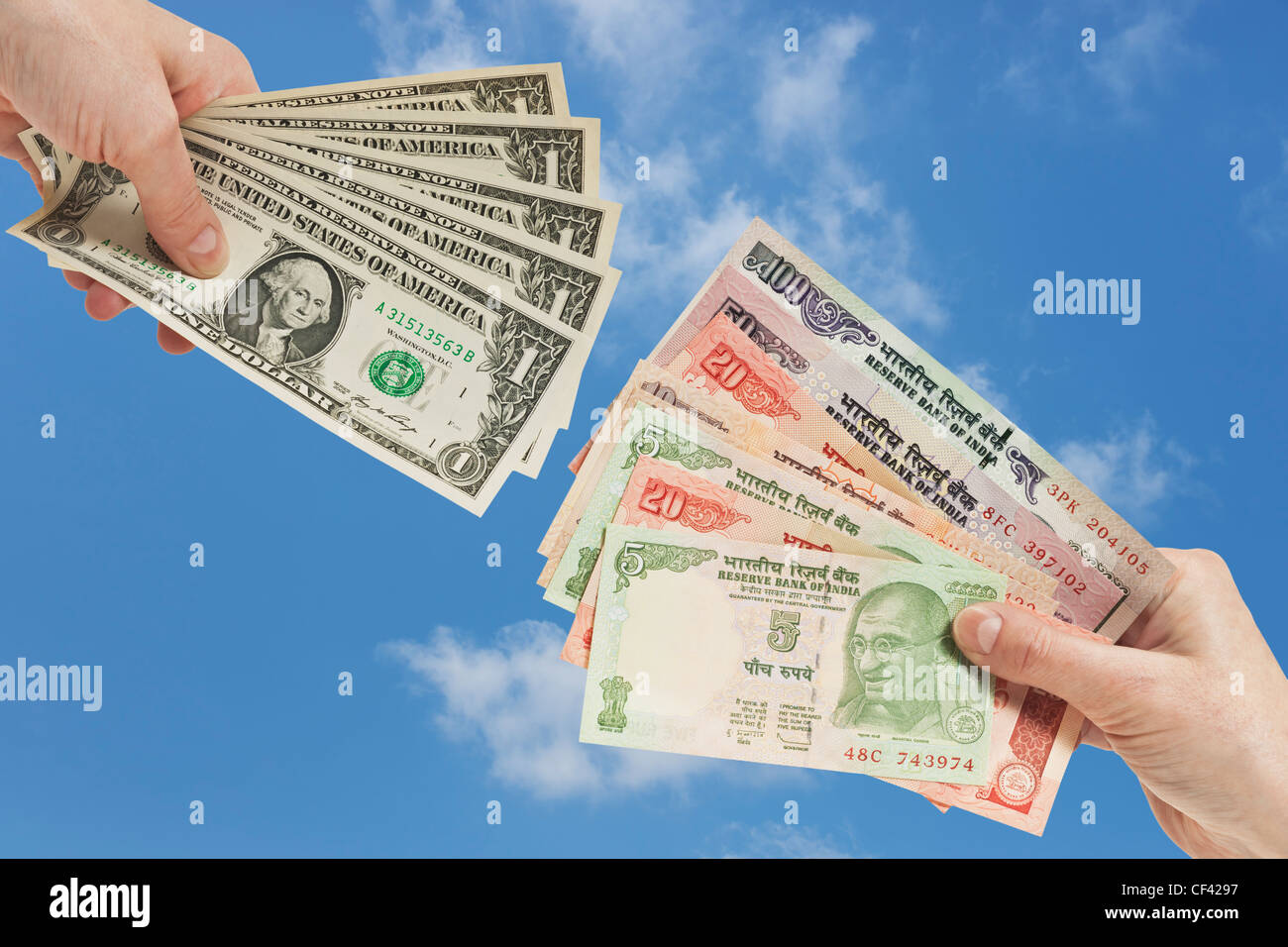 Cinque 1 U.S. Le fatture del dollaro sono tenute in mano. In corrispondenza dell'altro lato molte rupie indiane le fatture sono tenute in mano, sfondo cielo Foto Stock