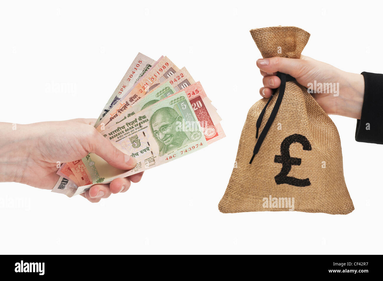 Molti diversi rupia indiana le fatture sono tenute in mano. Dall'altro lato un sacco di denaro con cancelletto cambio segno tenuto in mano. Foto Stock