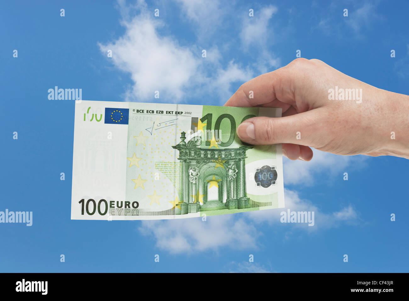 Un Euro 100 bill è tenuto in mano. Il 01 gennaio 2002 l'Euro è stato introdotto come denaro contante. Il cielo è in background. Foto Stock