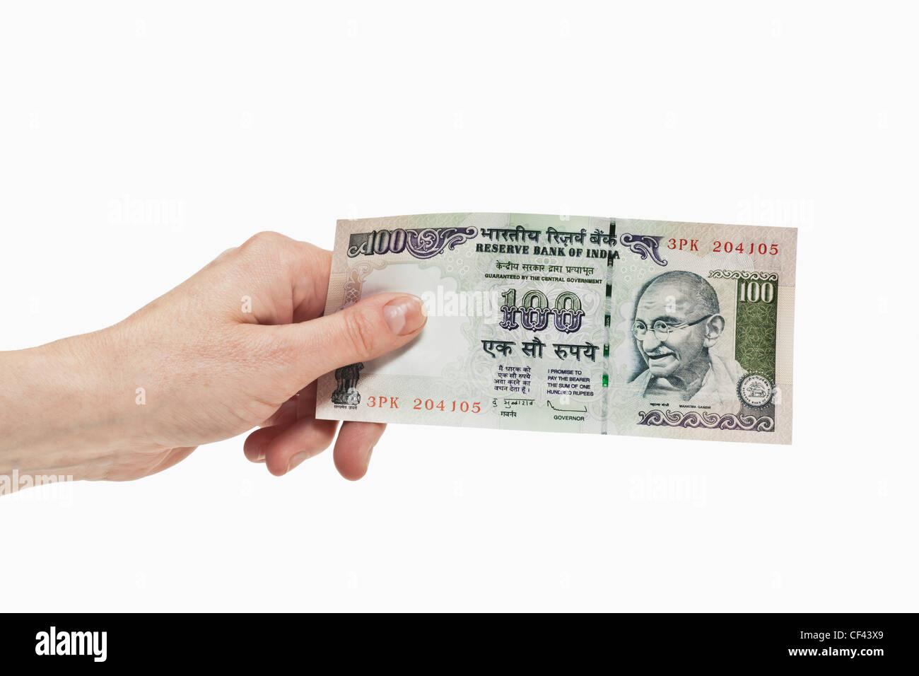 Un indiano 100 rupie bill con il ritratto del Mahatma Gandhi è tenuto in mano, sfondo bianco. Foto Stock