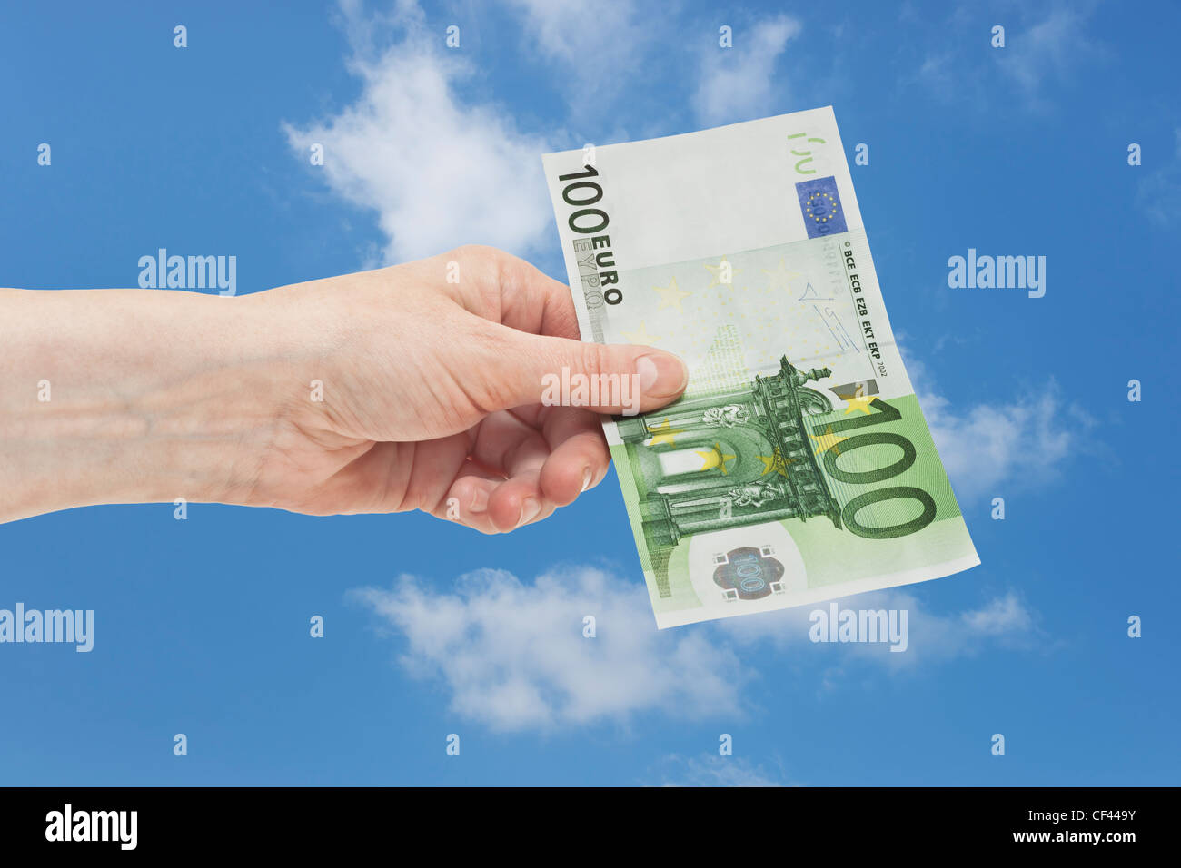 Un Euro 100 bill è tenuto in mano. Il 01 gennaio 2002 l'Euro è stato introdotto come denaro contante. Il cielo è in background. Foto Stock