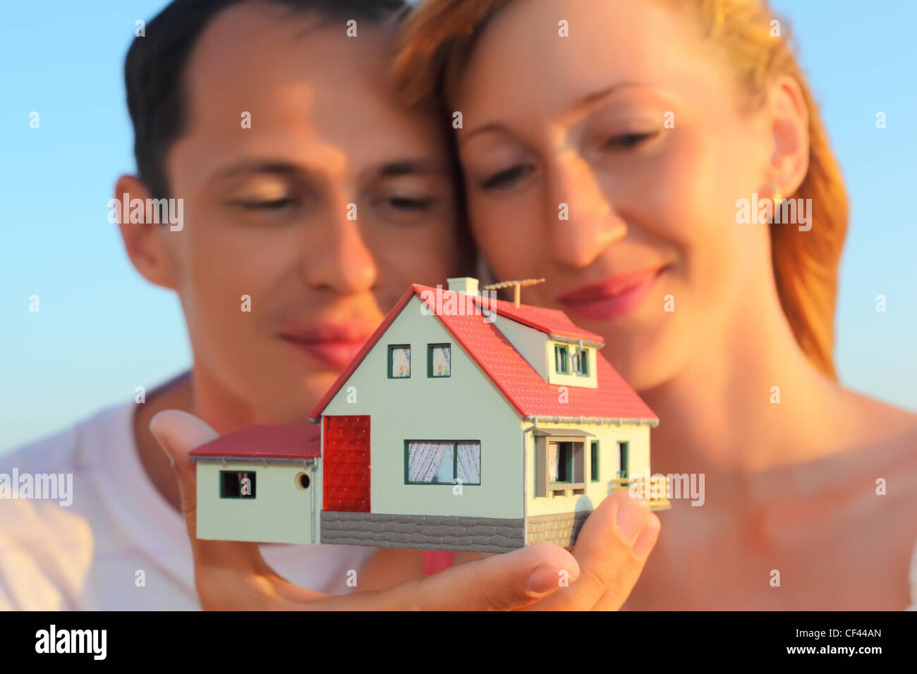 Giovane donna e uomo mantenendo in mani modello di casa con garage Foto Stock